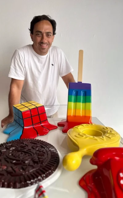 Polito en su taller junto a un cubo Rubik derretido, una paleta arcoíris, una galleta y un teléfono amarillo